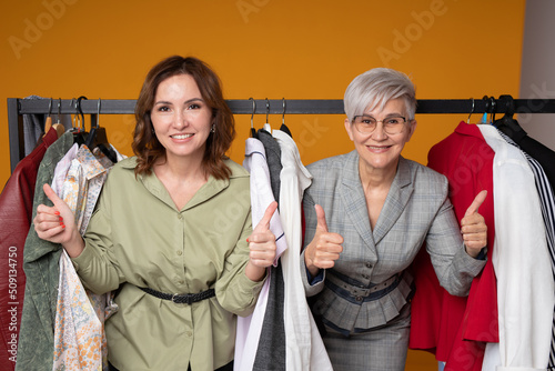 two adult women in a clothing store with a hand gesture