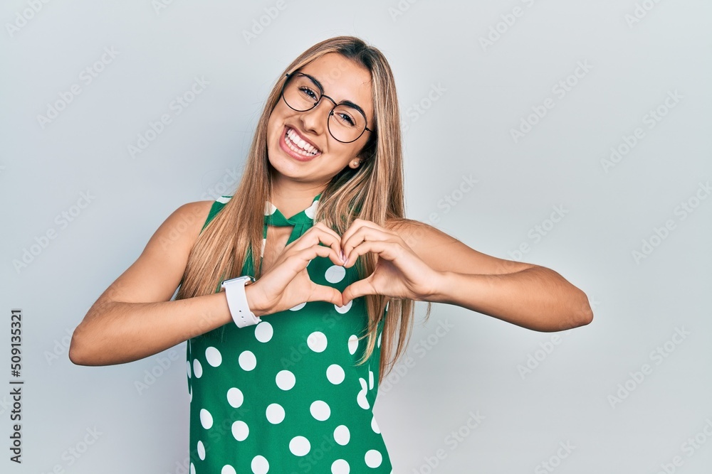 Beautiful hispanic woman wearing elegant shirt and glasses smiling in love doing heart symbol shape with hands. romantic concept. Beautiful hispanic woman wearing elegant shirt and glasses smiling in love doing heart symbol shape with hands. romantic concept.