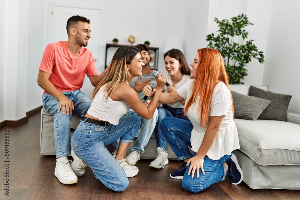 Group of young friends having party singing song using microphone at home. Group of young friends having party singing song using microphone at home.