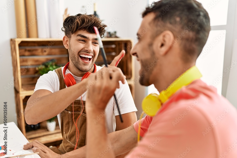 Obraz premium Two hispanic men couple smiling confident painting palm hands at art studio