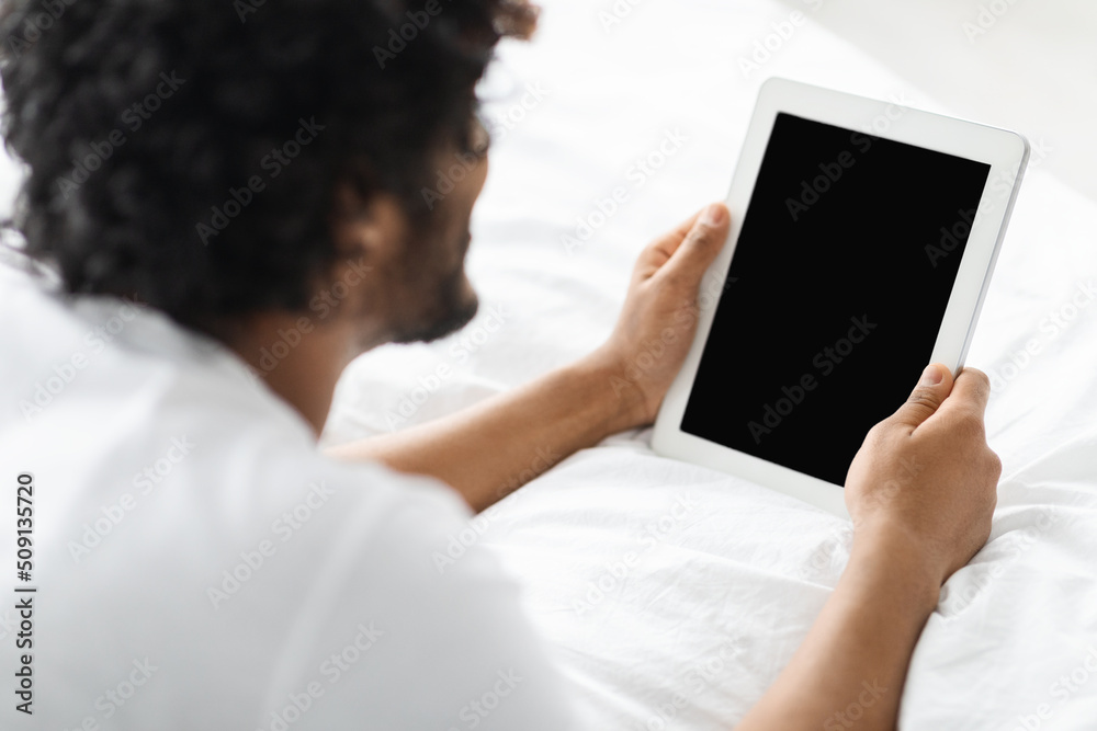 Dark-skinned man using digital tablet with blank screen