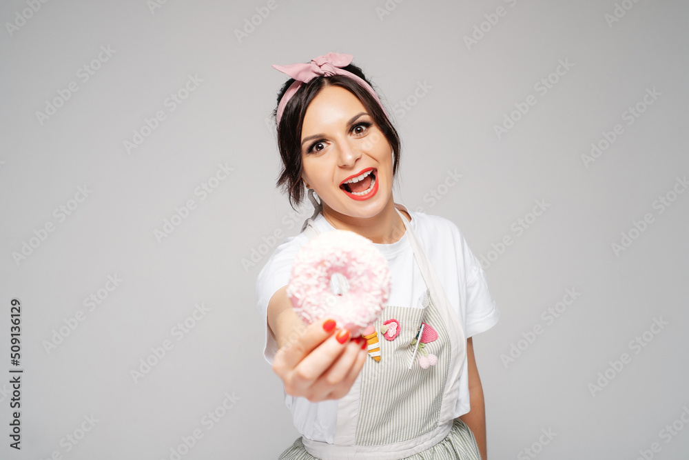 Smiling girl chef confectioner in apron holding donuts. Food cake concept. Smiling girl chef confectioner in apron holding donuts. Food cake concept.