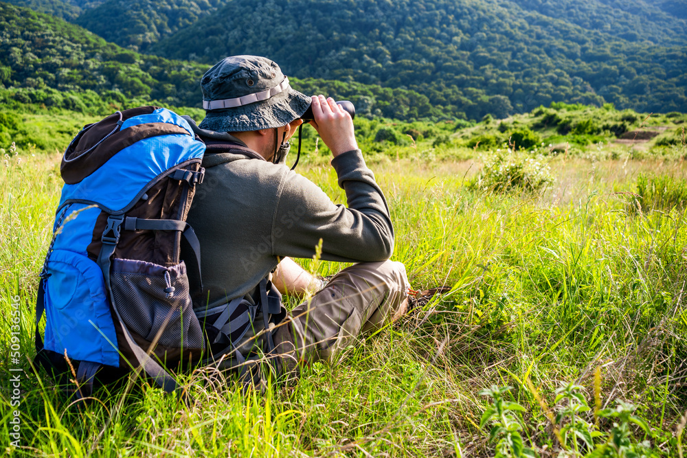 Image of man hiking and using binoculars.