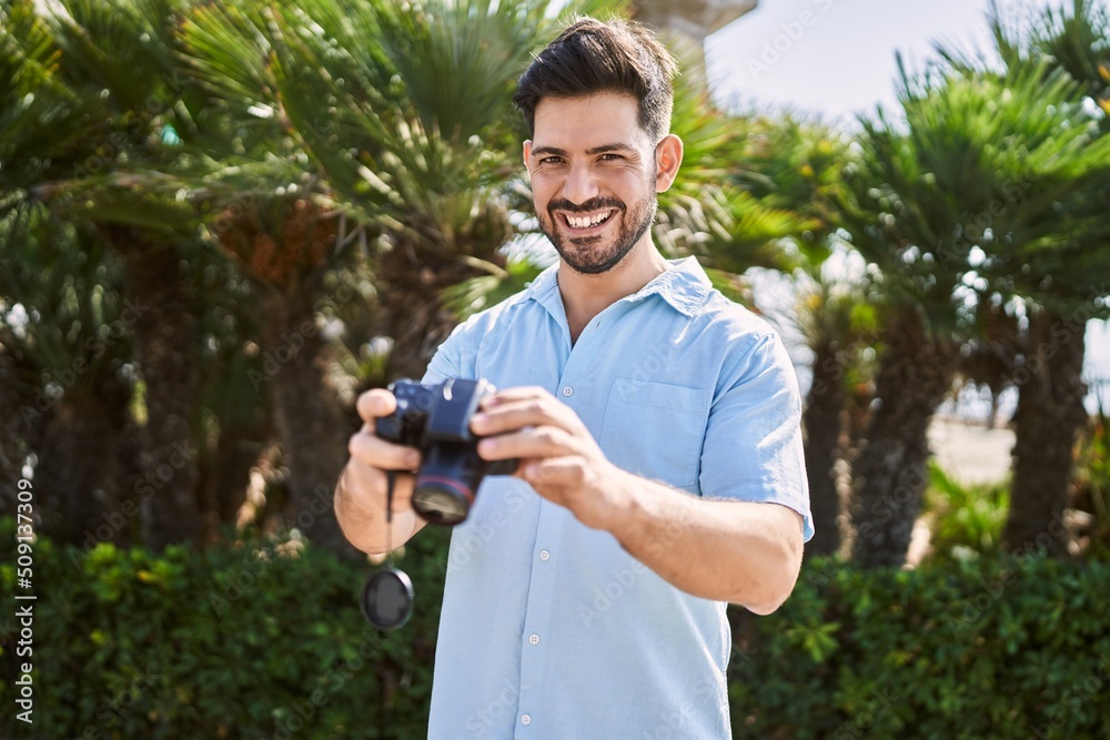 Young hispanic man smiling happy holding professional camera at the city. Young hispanic man smiling happy holding professional camera at the city.