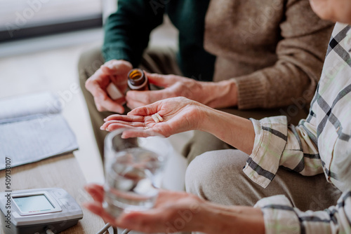 Close-up of senior man giving his wife medication at home