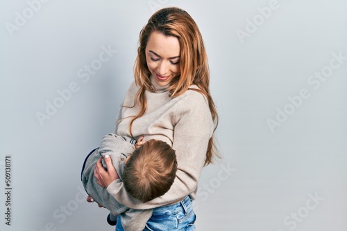 Young caucasian woman holding and hugging her son breastfeeding him, maternity lactation