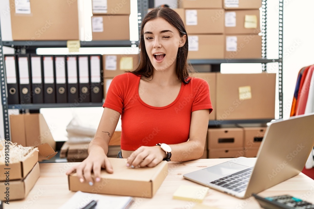 Young hispanic woman preparing order working at storehouse winking looking at the camera with sexy expression, cheerful and happy face. Young hispanic woman preparing order working at storehouse winking looking at the camera with sexy expression, cheerful and happy face.