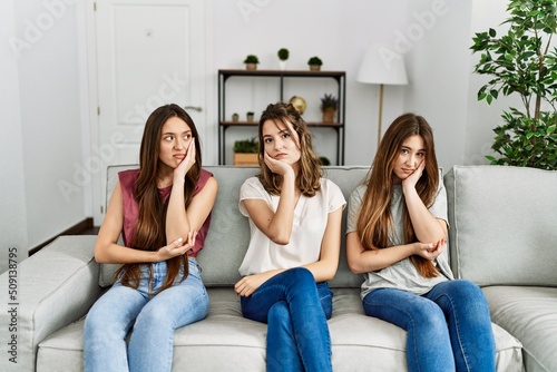 Group of three hispanic girls sitting on the sofa at home thinking looking tired and bored with depression problems with crossed arms.