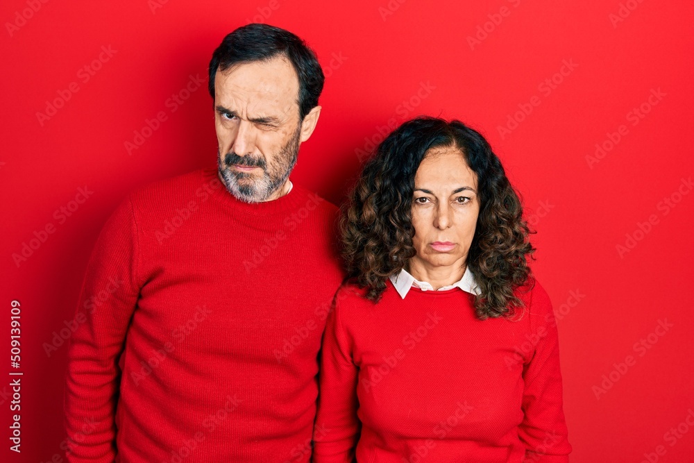 Middle age couple of hispanic woman and man hugging and standing together skeptic and nervous, frowning upset because of problem. negative person. Middle age couple of hispanic woman and man hugging and standing together skeptic and nervous, frowning upset because of problem. negative person.