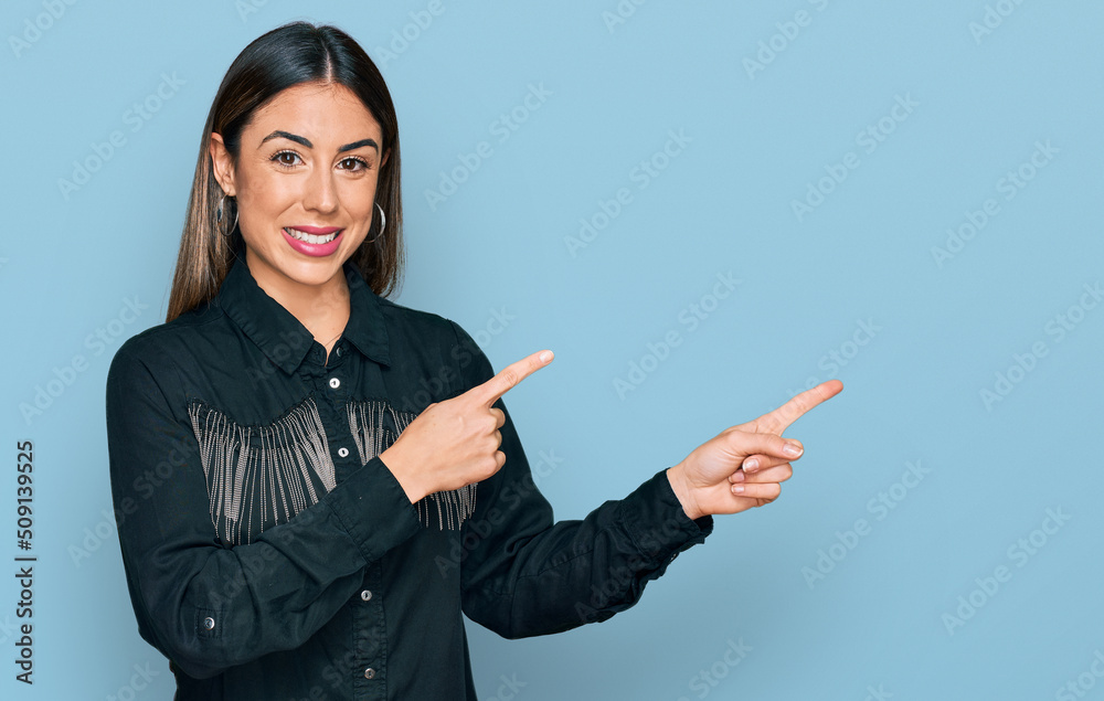 Young hispanic woman wearing casual clothes smiling and looking at the camera pointing with two hands and fingers to the side. Young hispanic woman wearing casual clothes smiling and looking at the camera pointing with two hands and fingers to the side.