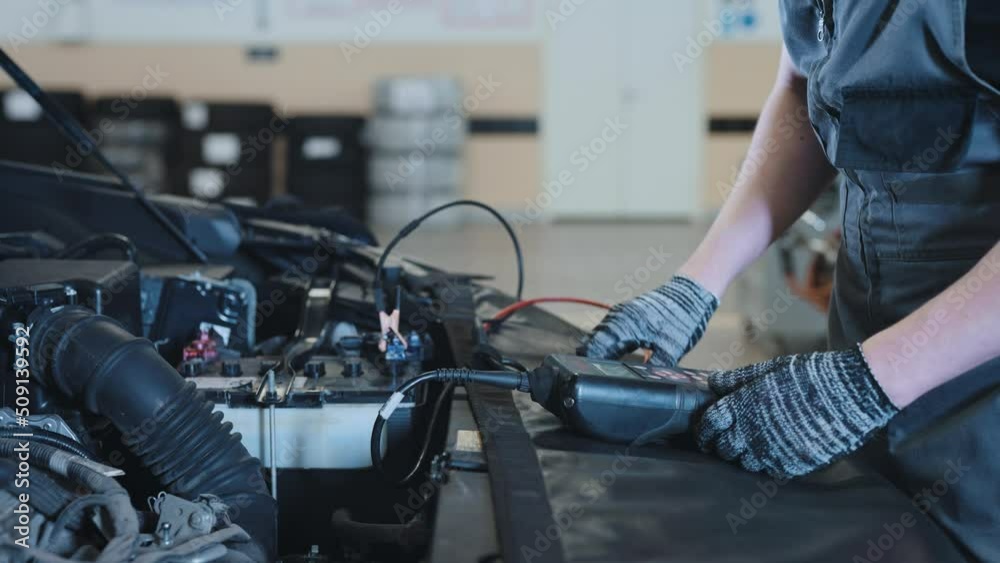 A mechanic at a car service station checking the battery.