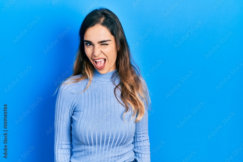Young hispanic girl wearing casual clothes winking looking at the camera with sexy expression, cheerful and happy face. Young hispanic girl wearing casual clothes winking looking at the camera with sexy expression, cheerful and happy face.