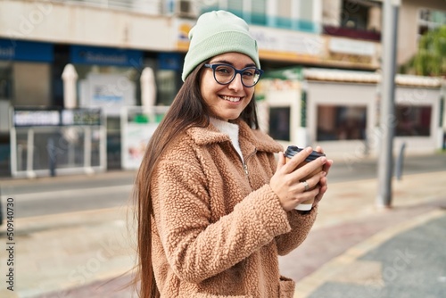 Young hispanic woman smiling confident drinking coffee at street