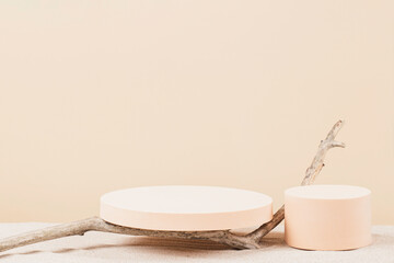 Two empty round beige platform podiums and dry tree twigs on white beach sand background. Minimal creative composition background for cosmetics or products presentation. Front view