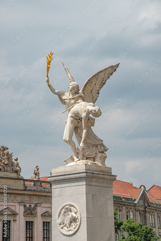 Roman statue of an angel holding a fighter at war at Schloss Bridge near Berlin Cathedral and Unter den Linden street in historical and museum downtown of Berlin, Germany.