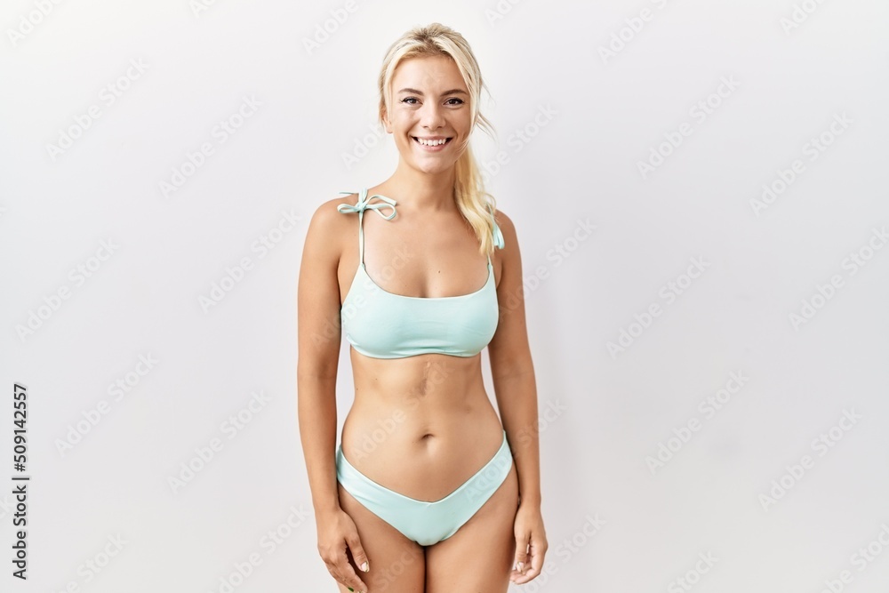 Young caucasian woman wearing bikini over isolated background with a happy and cool smile on face. lucky person. Young caucasian woman wearing bikini over isolated background with a happy and cool smile on face. lucky person.
