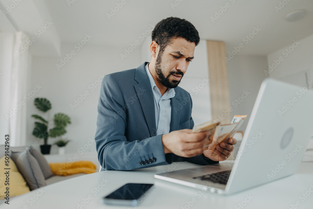 Depressed businessman man counting euro money working on computer at office desk, inflation concept. Depressed businessman man counting euro money working on computer at office desk, inflation concept.