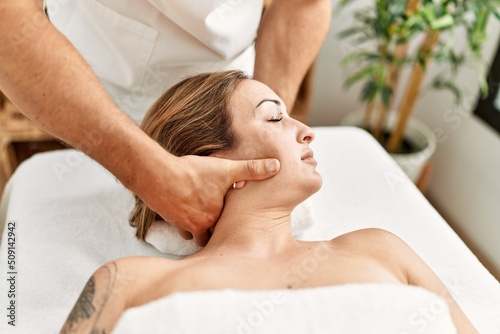 Young caucasian woman at physiotherapy clinic getting muscle massage by professional therapist. Physiotherapist man doing cervical treatment to client