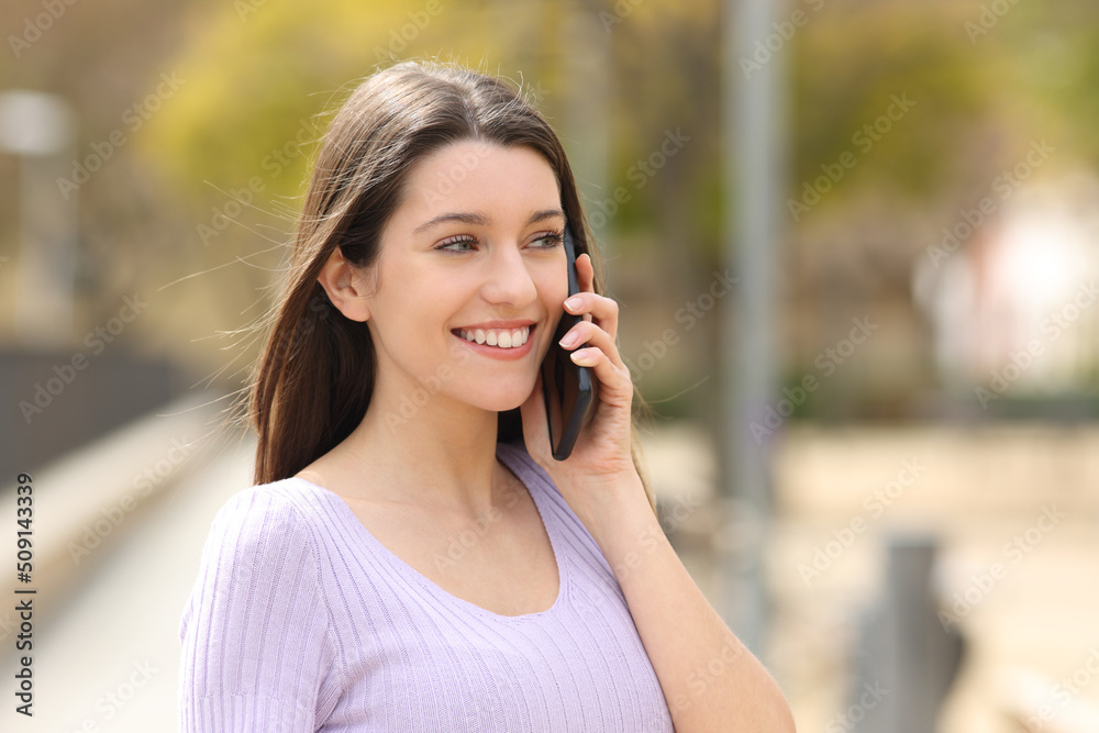 Happy teen calling on phone walking in a park Happy teen calling on phone walking in a park