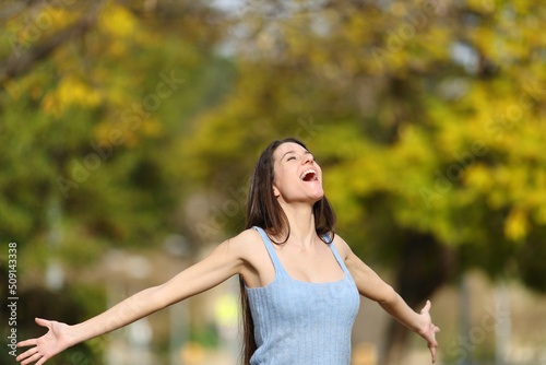 Fototapeta Naklejka Na Ścianę i Meble -  Excited teen screaming outstretching arms in a park
