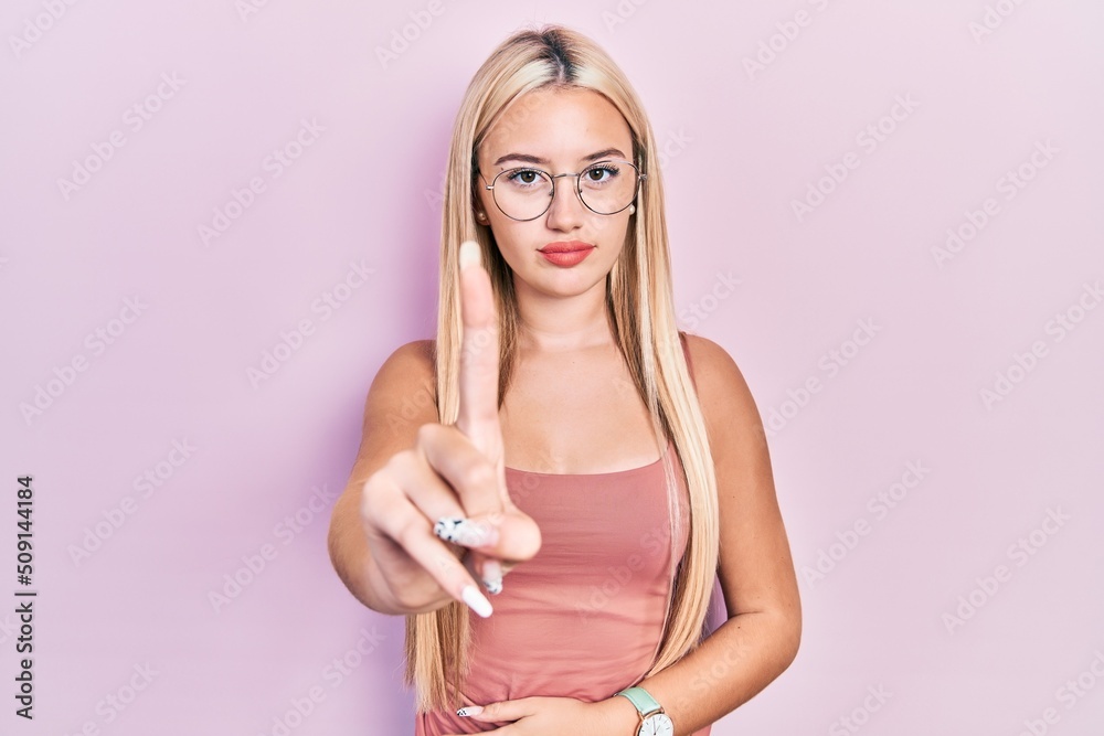 Young blonde girl wearing casual clothes pointing with finger up and angry expression, showing no gesture Young blonde girl wearing casual clothes pointing with finger up and angry expression, showing no gesture