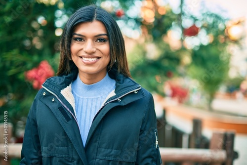 Beautiful hispanic woman smiling confient by christmas decorations photo