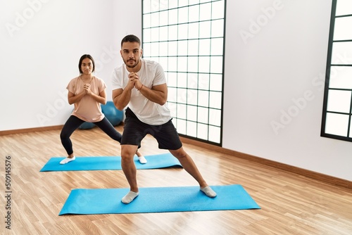 Latin man and woman couple stretching at sport center