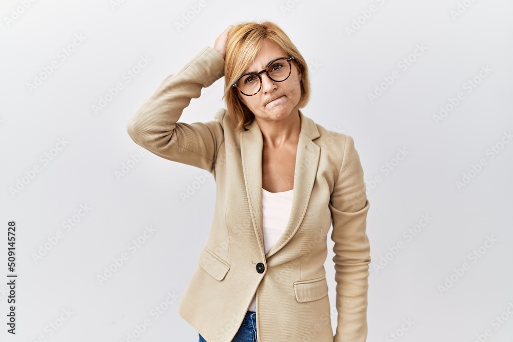 Middle age blonde business woman standing over isolated background confuse and wondering about question. uncertain with doubt, thinking with hand on head. pensive concept. Middle age blonde business woman standing over isolated background confuse and wondering about question. uncertain with doubt, thinking with hand on head. pensive concept.