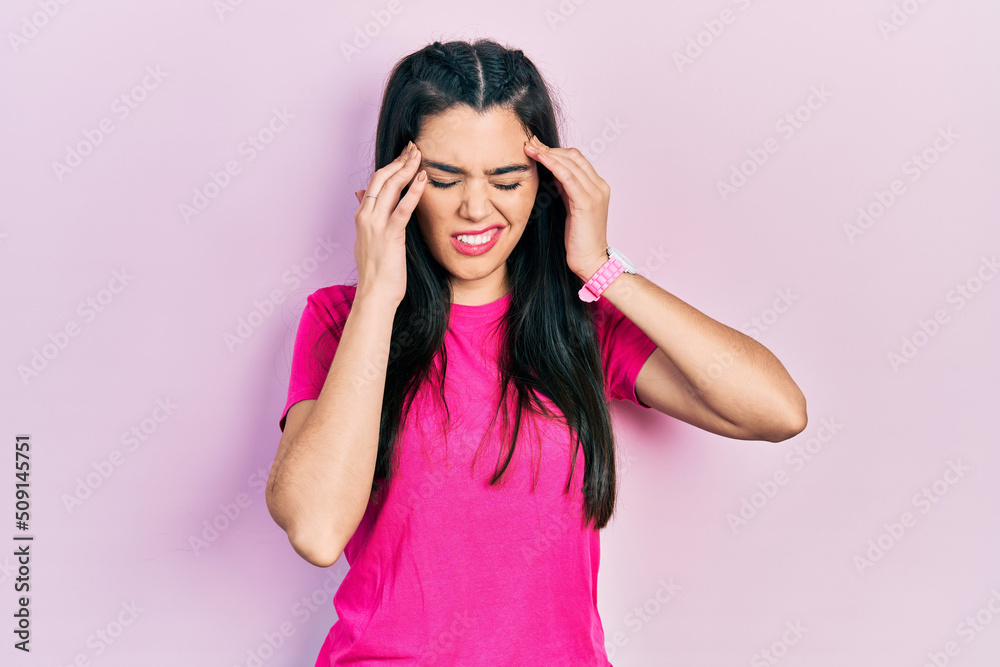 Young hispanic girl wearing casual pink t shirt with hand on head, headache because stress. suffering migraine.