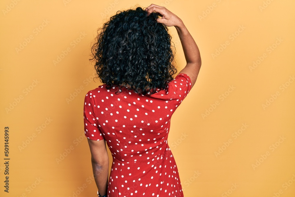 Young latin girl wearing summer dress backwards thinking about doubt with hand on head Young latin girl wearing summer dress backwards thinking about doubt with hand on head
