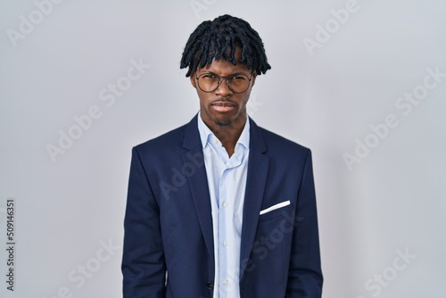 Obraz na plátně Young african man with dreadlocks wearing business jacket over white background skeptic and nervous, frowning upset because of problem
