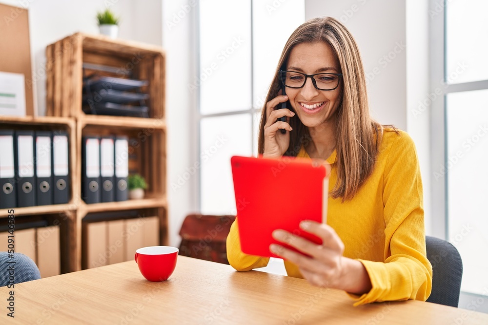 Young woman business worker talking on the smartphone using touchpad at office Young woman business worker talking on the smartphone using touchpad at office