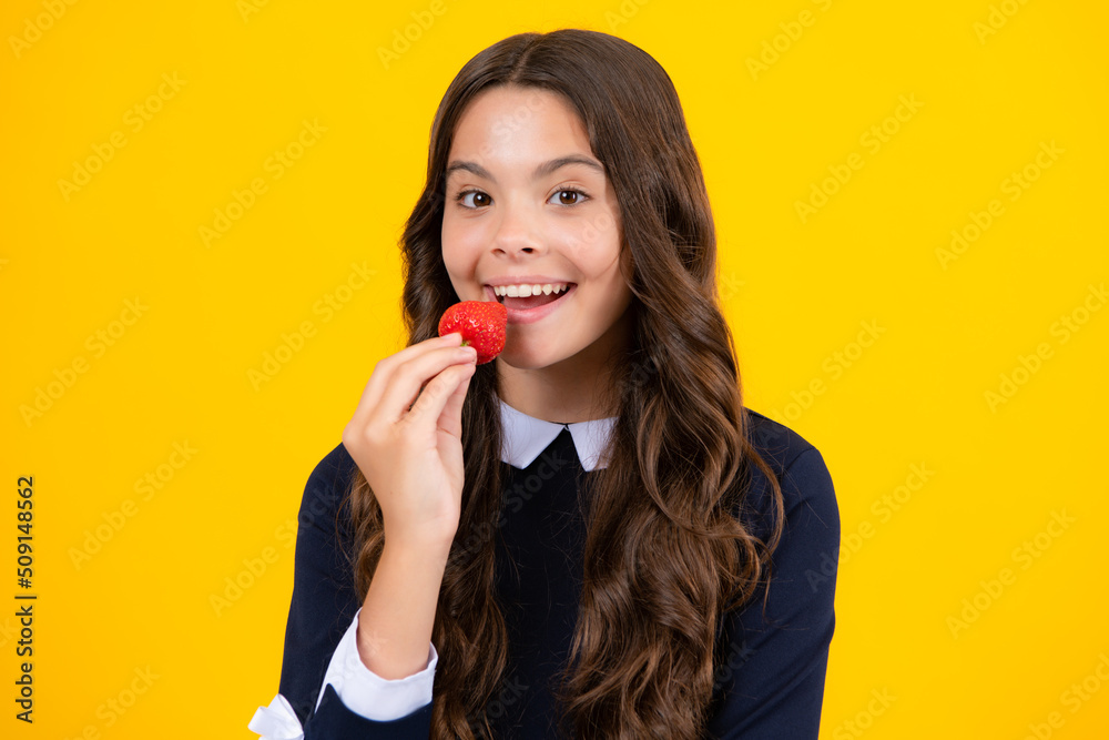 Child eating a strawberries. Happy teen child picking fruit strawberry bowl on yellow background. Healthy natural organic vitamin food for kids, strawberry season. Child eating a strawberries. Happy teen child picking fruit strawberry bowl on yellow background. Healthy natural organic vitamin food for kids, strawberry season.