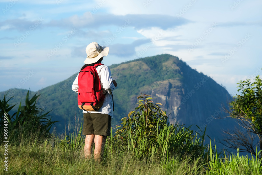 Happy female hiker with a backpack stands on top of a mountain enjoying nature and looking at the sky. Freedom and happiness, achievement in mountains. Happy female hiker with a backpack stands on top of a mountain enjoying nature and looking at the sky. Freedom and happiness, achievement in mountains.
