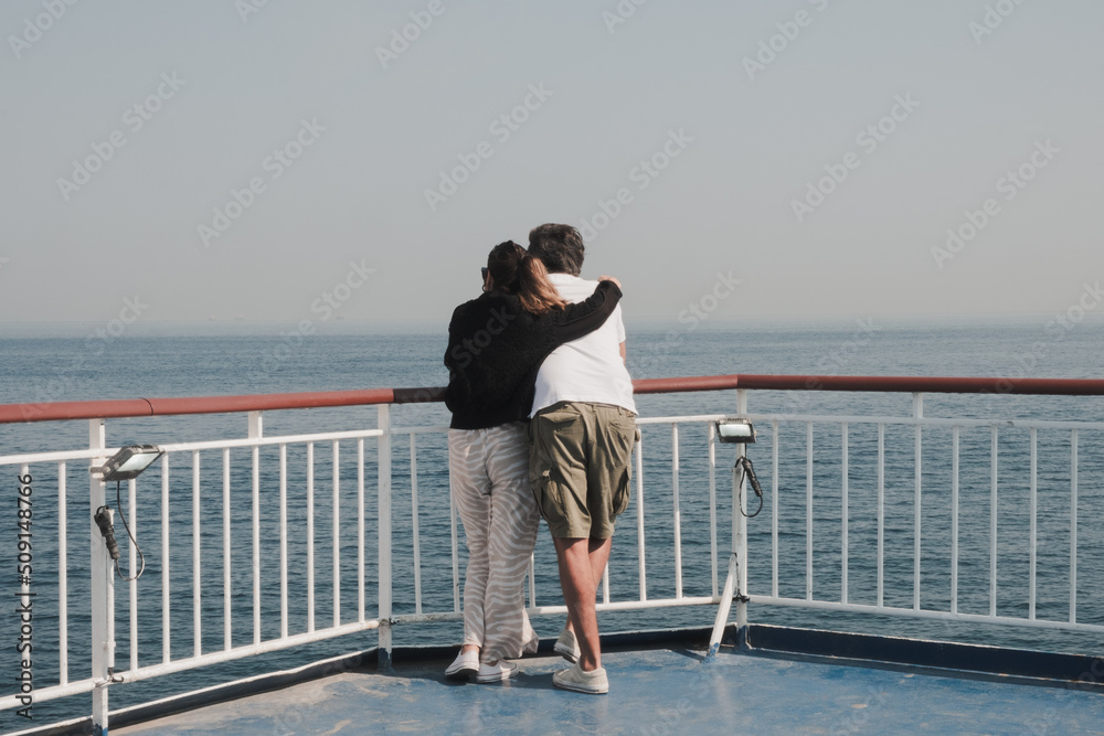 Couple embracing on a boat, looking at the sea horizon Couple embracing on a boat, looking at the sea horizon