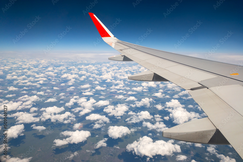 Plane wing with blue clear sky and white clouds oover the  summer ground travel or vacation concept