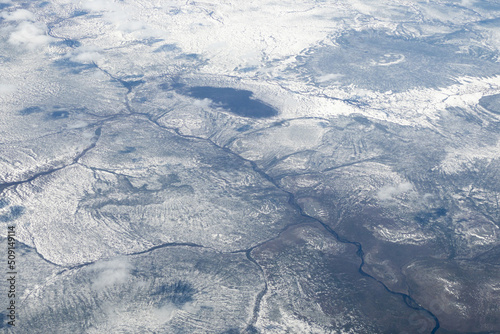 Aerial shot of snowy forested mountain tops, with stratospheric clouds