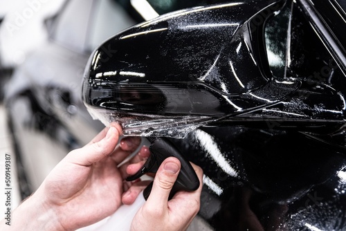 Obraz na płótnie Car detailing technician applying transparent ppf foil on car body w salonie