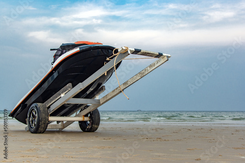 A jet ski loaded on a transit cart on a sea beach at sunset