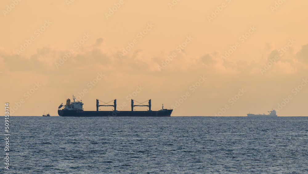 Nautical vessels in the horizon, evening seascape shot in Galle fort. Large cargo ships and small fishing boats.