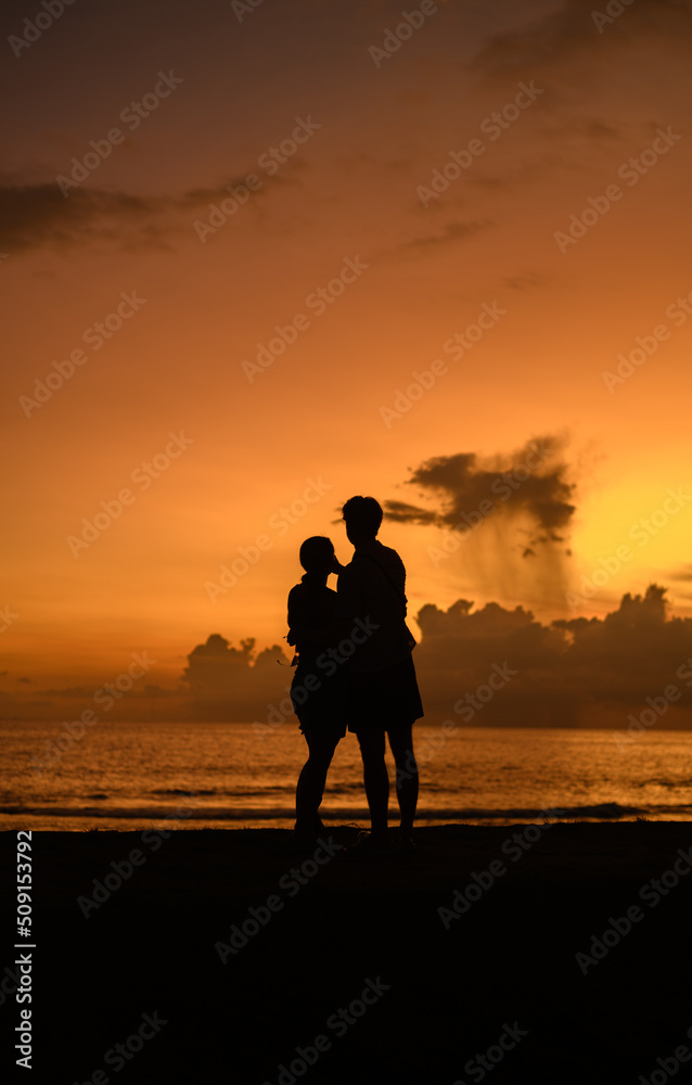 Enjoying the evening, silhouetted couple standing close to each other, Beautiful golden sunset in the background.