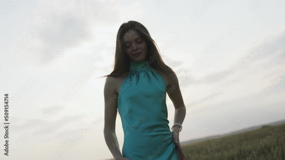 Young beautiful woman in long turquoise dress in summer field. Concept of freedom. walking in amazing green field Young beautiful woman in long turquoise dress in summer field. Concept of freedom. walking in amazing green field