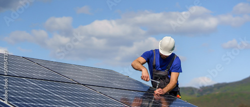 Man worker installing solar photovoltaic panels on roof, alternative energy concept. photo