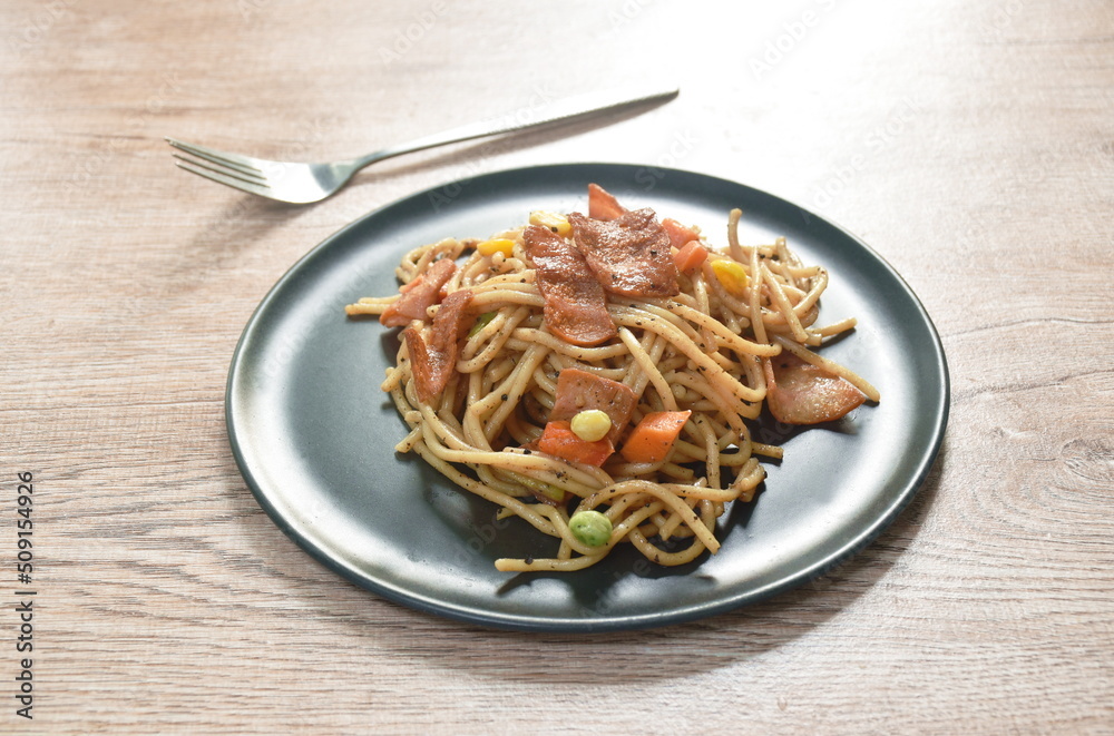 fried spaghetti black pepper sauce topping crispy bacon and corn with green pea on plate fried spaghetti black pepper sauce topping crispy bacon and corn with green pea on plate