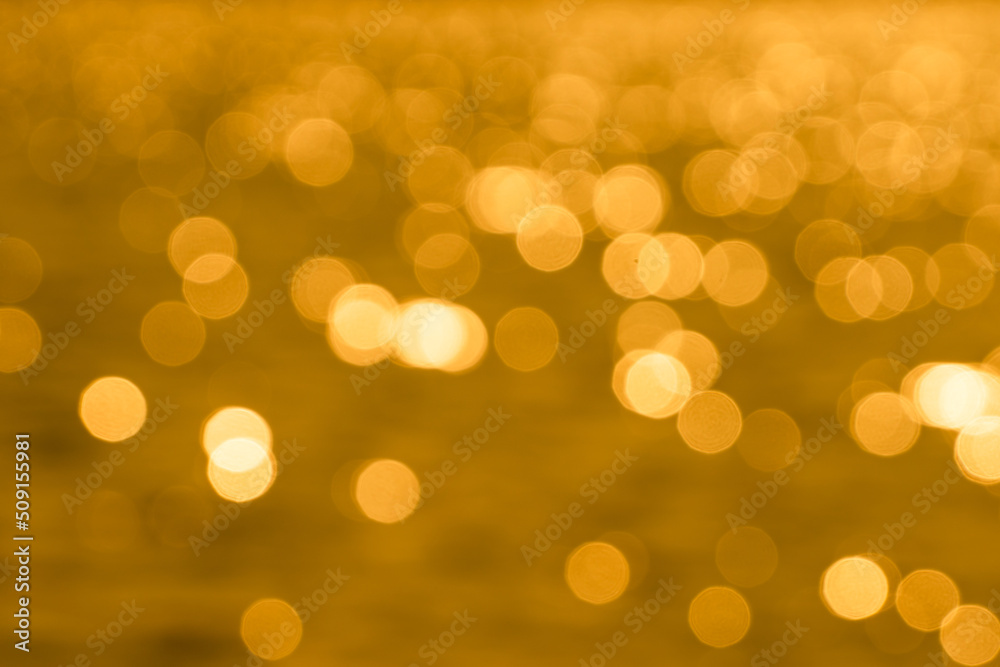 Bokeh light from reflection of golden water surface in the evening sunset