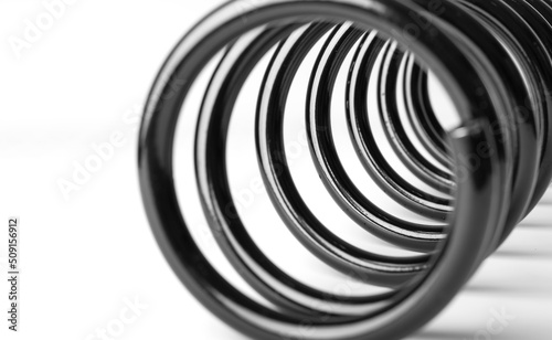 Black shock absorber spring in perspective on a white background. Car parts concept