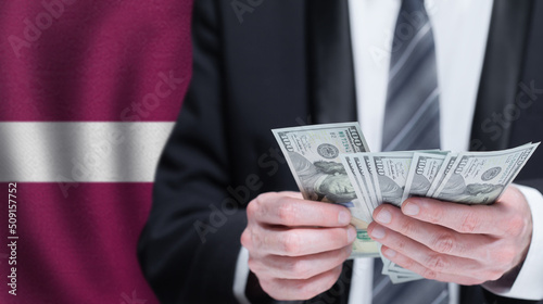 Hands holding dollar money on flag of Latvia