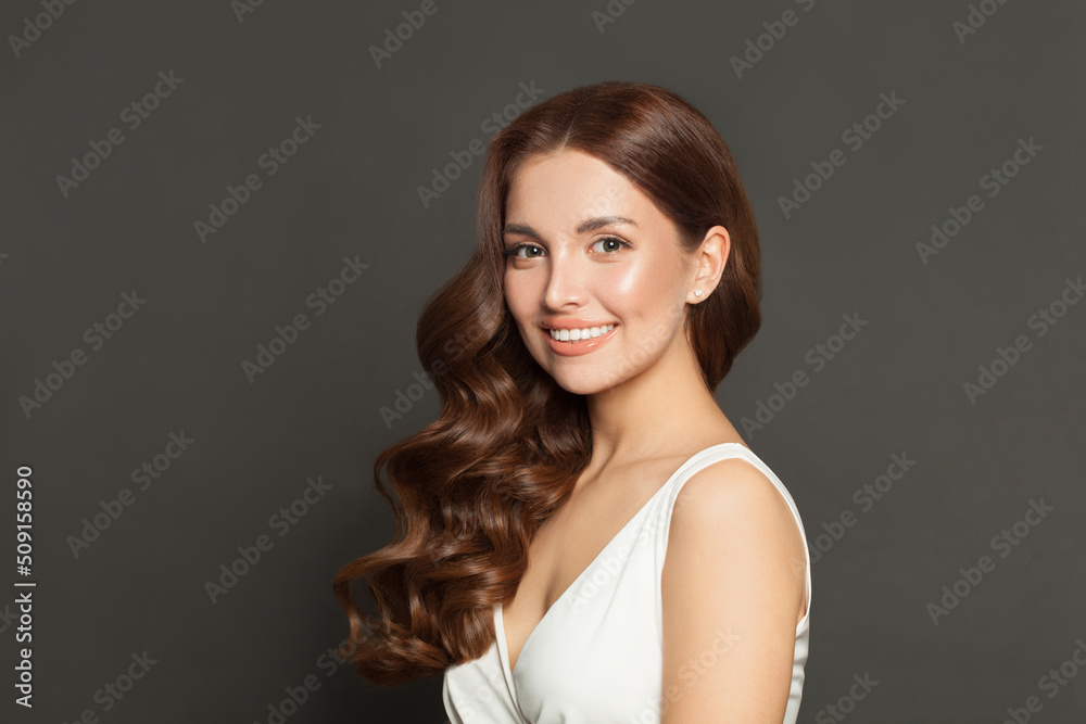 Young woman with healthy skin, natural makeup and wavy brown hair smiling and looking at camera Young woman with healthy skin, natural makeup and wavy brown hair smiling and looking at camera