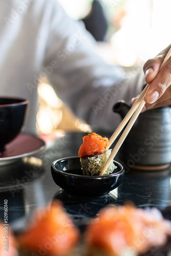 Comiendo uramaki de tempura de salmón en un restaurante japonés. Mojando el sushi en soja.