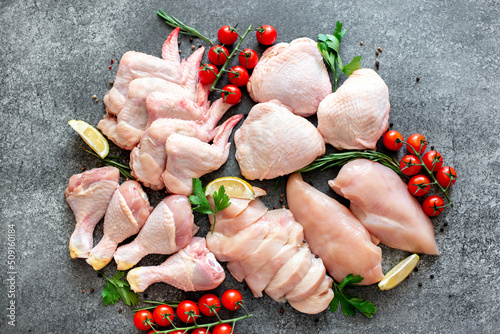 Set of raw chicken fillet, thigh, wings, strips and legs on a stone background of a culinary table with spices photo